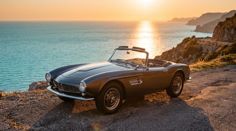 Vintage roadster parked on a coastal cliff road at sunset