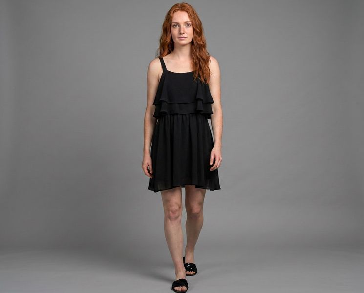 A model in a black dress photographed against a plain grey studio backdrop